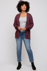 woman wearing a burgundy knitted cardigan over a grey top, paired with light blue jeans and black ankle boots