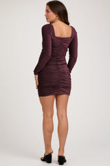 woman wearing a burgundy long sleeve ruched maternity dress with a square neckline, showing a fitted silhouette