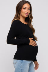 woman wearing a black long sleeve maternity top and holding her baby bump