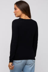 woman wearing a black long sleeve maternity sweater, shown from the back with light blue jeans