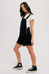 woman wearing black corduroy overalls with a white t-shirt, paired with black high-top sneakers