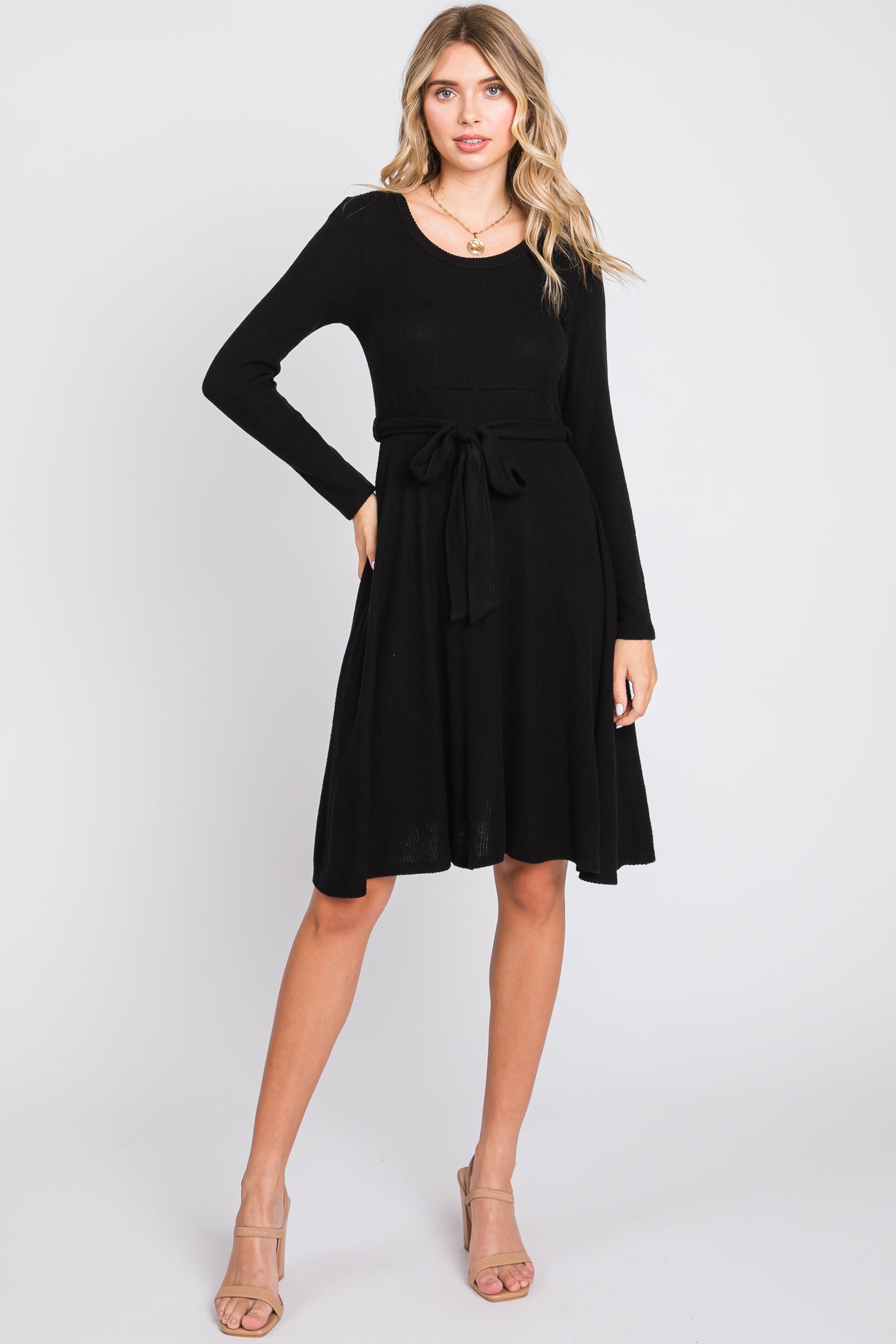 woman wearing a black long sleeve knit dress with a belted waist and flared skirt