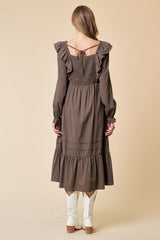 woman wearing a brown long sleeve dress with ruffle details and tiered hem, paired with white cowboy boots