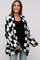 woman wearing a black and white checkered maternity cardigan over a black top and showing her baby bump