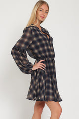 woman wearing a navy plaid long sleeve dress with a cinched waist and flared skirt