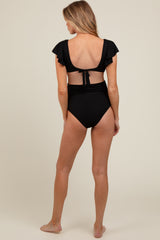 woman wearing a black maternity swimsuit with ruffled sleeves and a tie-back detail