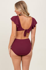 woman wearing a burgundy ribbed bikini with flutter sleeves and a tied back, showing high-waisted bottoms