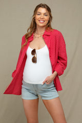 woman wearing a red checkered maternity shirt over a white tank top and denim shorts, showing her baby bump