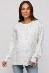 woman wearing a light grey speckled maternity sweater with a relaxed fit and long sleeves, showing her baby bump