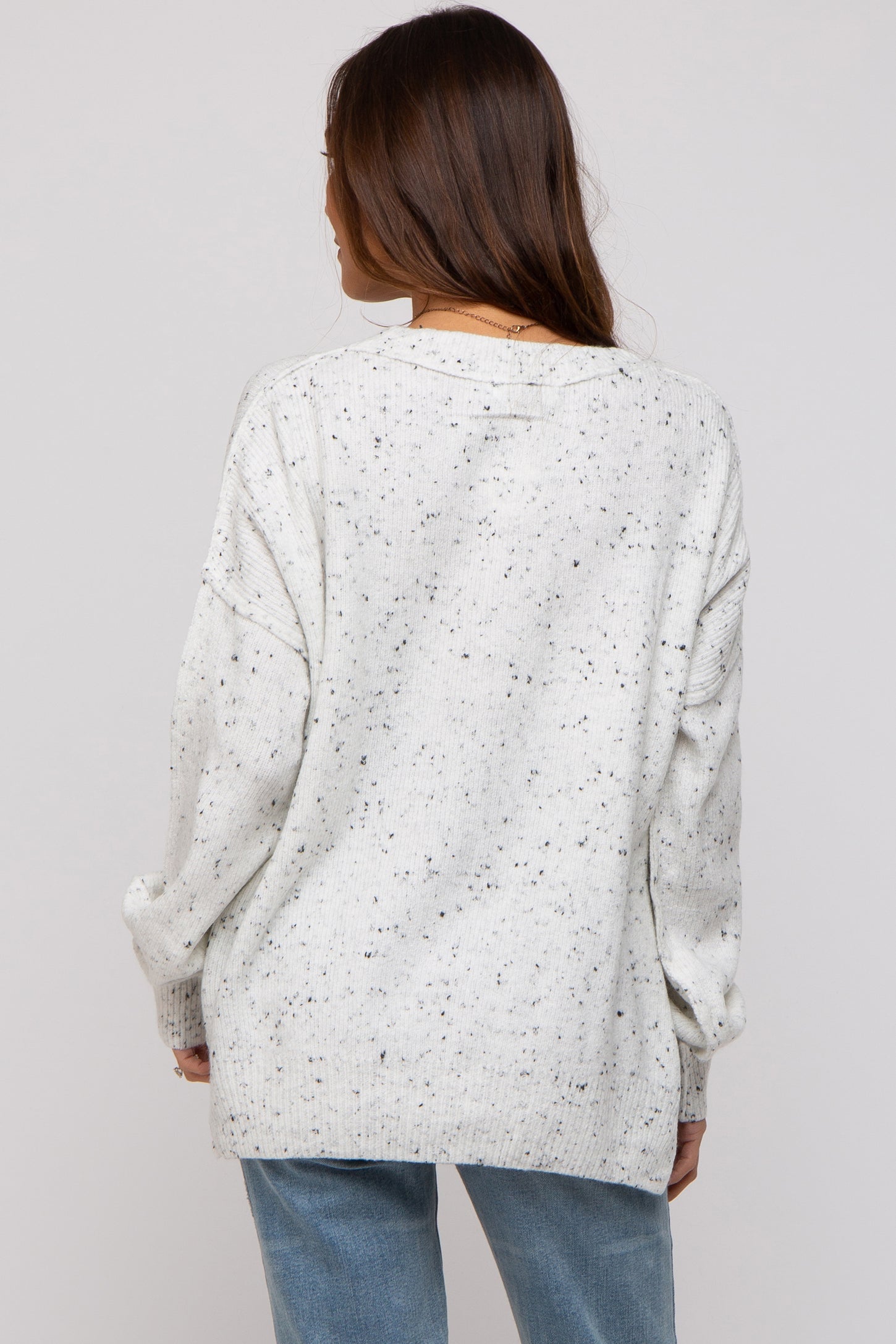 woman wearing a cream speckled oversized maternity sweater, viewed from the back