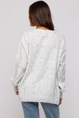 woman wearing a cream speckled oversized maternity sweater, viewed from the back