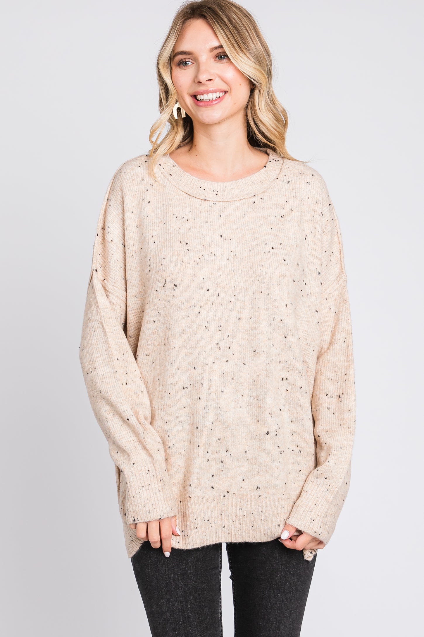 woman wearing a beige oversized sweater with speckled detailing and a relaxed fit