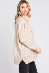 woman wearing a light beige oversized sweater with speckles and a side slit, styled with black skinny jeans