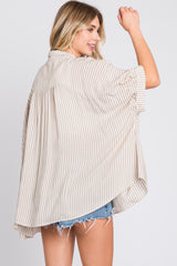 woman wearing a light beige and white striped oversized shirt with short sleeves and a flowy back, styled with denim shorts