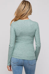 woman wearing a light green ribbed maternity top, seen from the back, paired with blue jeans