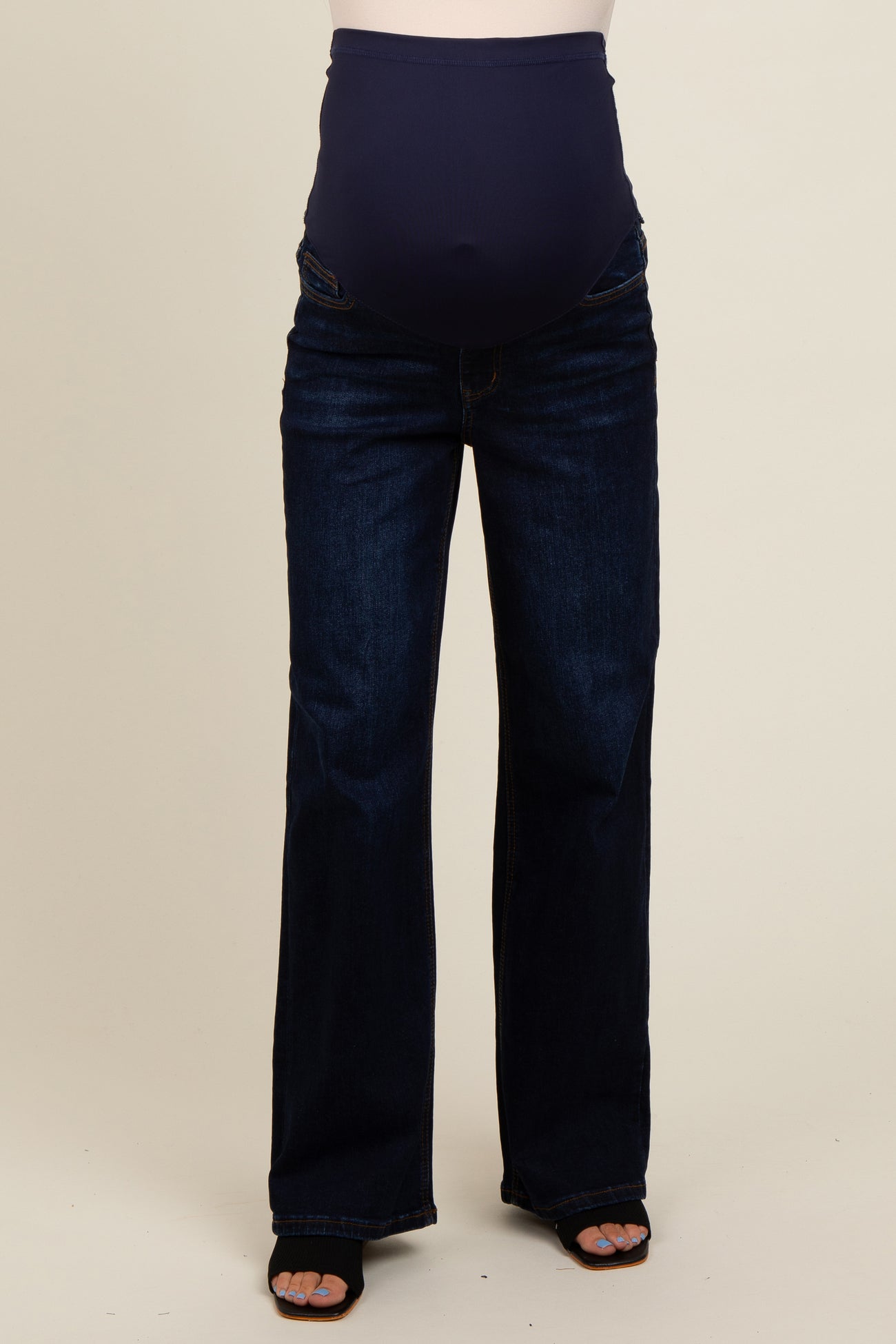 maternity wear dark wash bootcut jeans with a stretchy over-the-bump panel, model wearing them with black heels