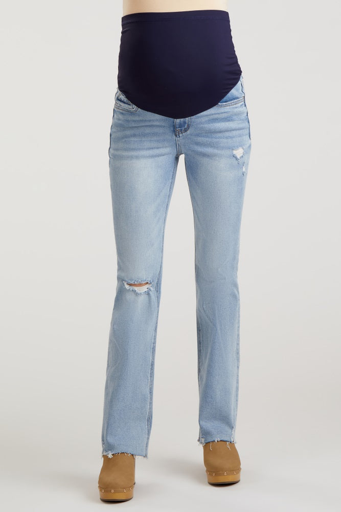 woman wearing light blue distressed maternity jeans with a dark blue supporting belly panel