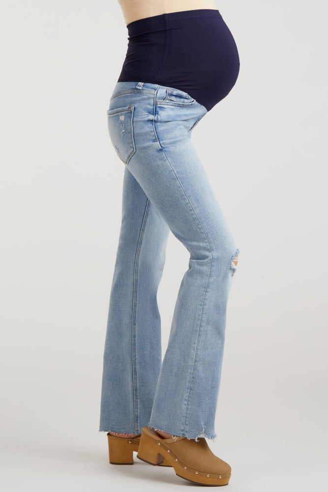woman wearing light wash distressed maternity flare jeans with a black belly panel and visible baby bump