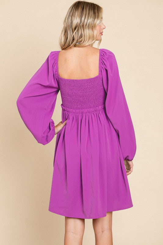 woman wearing a hot pink puff sleeve dress with a smocked bodice and flared skirt, shown from the back