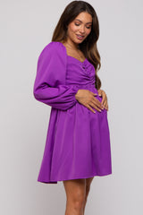woman wearing a purple long sleeve maternity dress and holding her baby bump