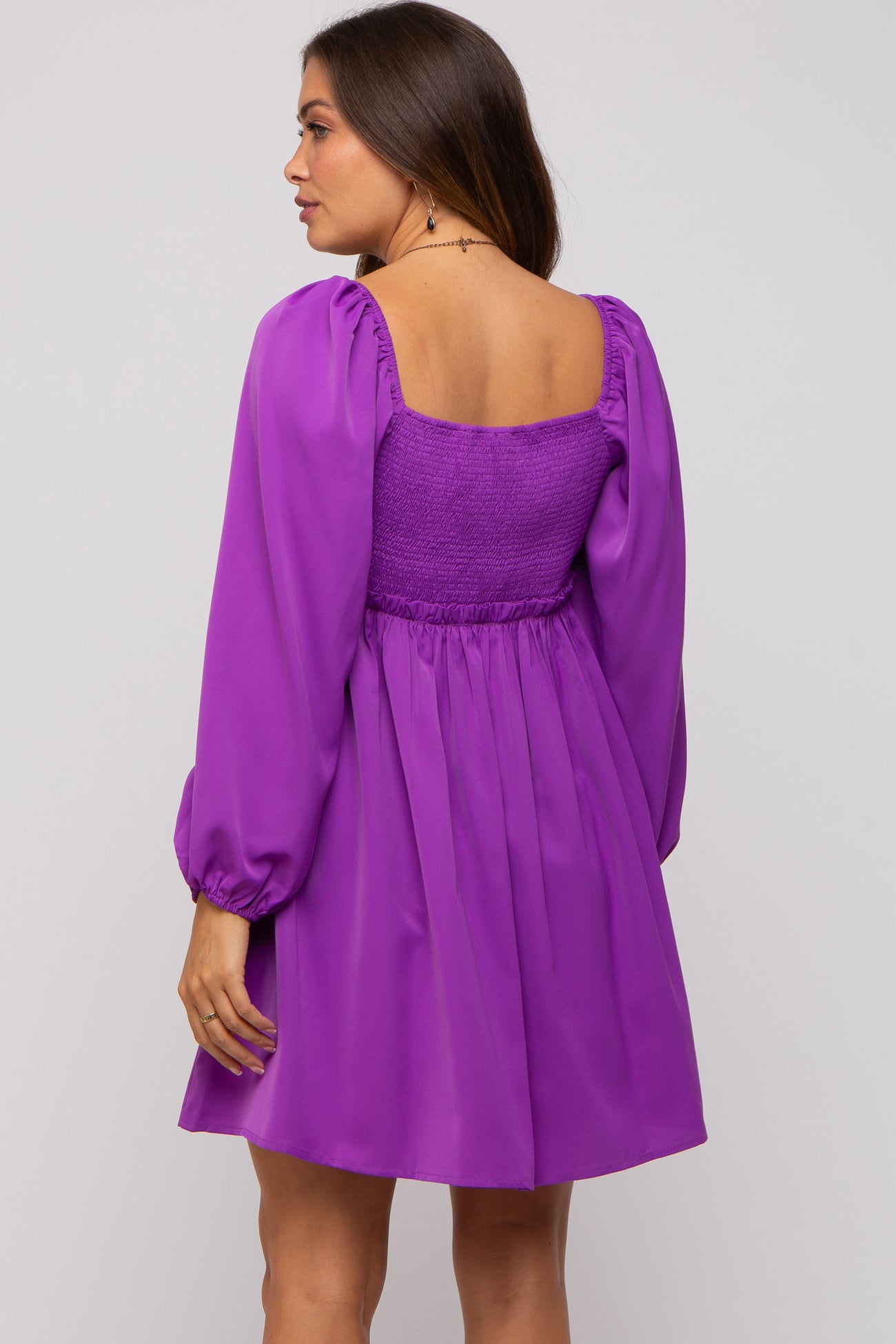 woman wearing a purple maternity dress with a smocked bodice and puffed sleeves, viewed from the back