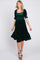woman wearing a dark green velvet dress with puff sleeves and a ruffled hem, standing with a smile