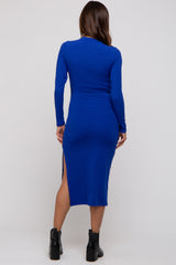 woman wearing a blue ribbed maternity dress with long sleeves and side slits, showing a fitted silhouette
