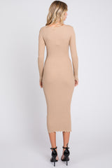 woman wearing a beige ribbed midi dress with long sleeves and a scalloped hem, standing with her back to the camera