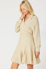 woman wearing a light beige wrap dress with long sleeves and a flared skirt