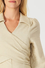 woman wearing a champagne-colored glittery wrap dress with puffed sleeves and a collared neckline