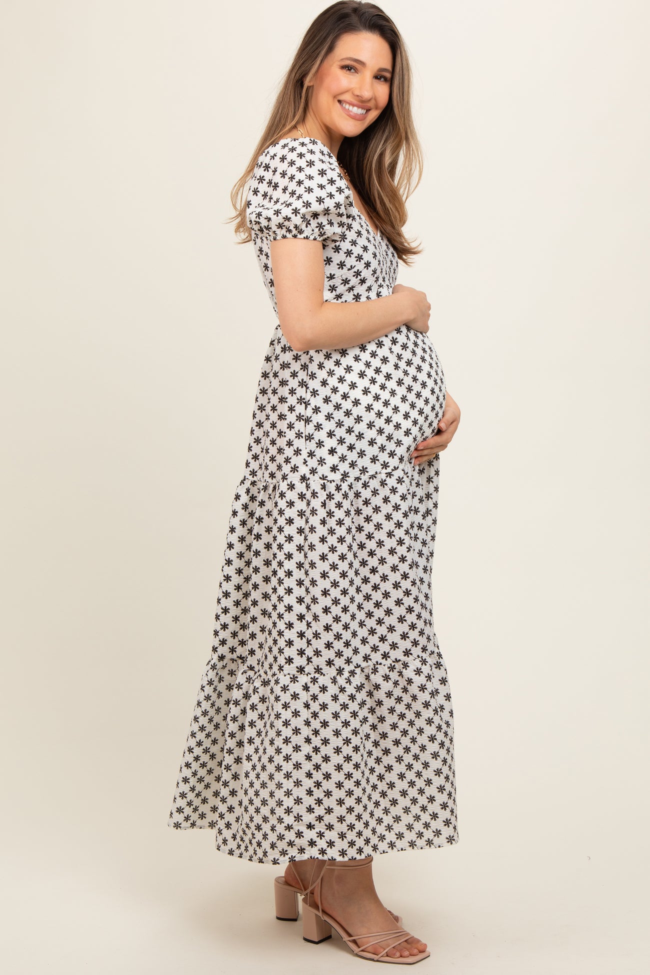woman wearing a black and white floral maternity maxi dress and holding her baby bump