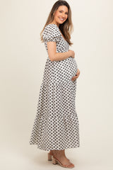 woman wearing a black and white floral maternity maxi dress and holding her baby bump