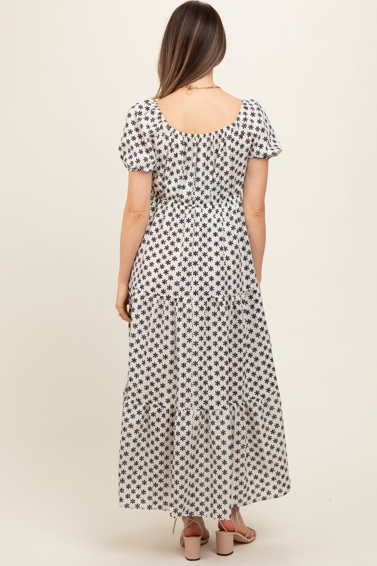 woman wearing a black and white floral print maternity maxi dress with short puff sleeves and tiered hem