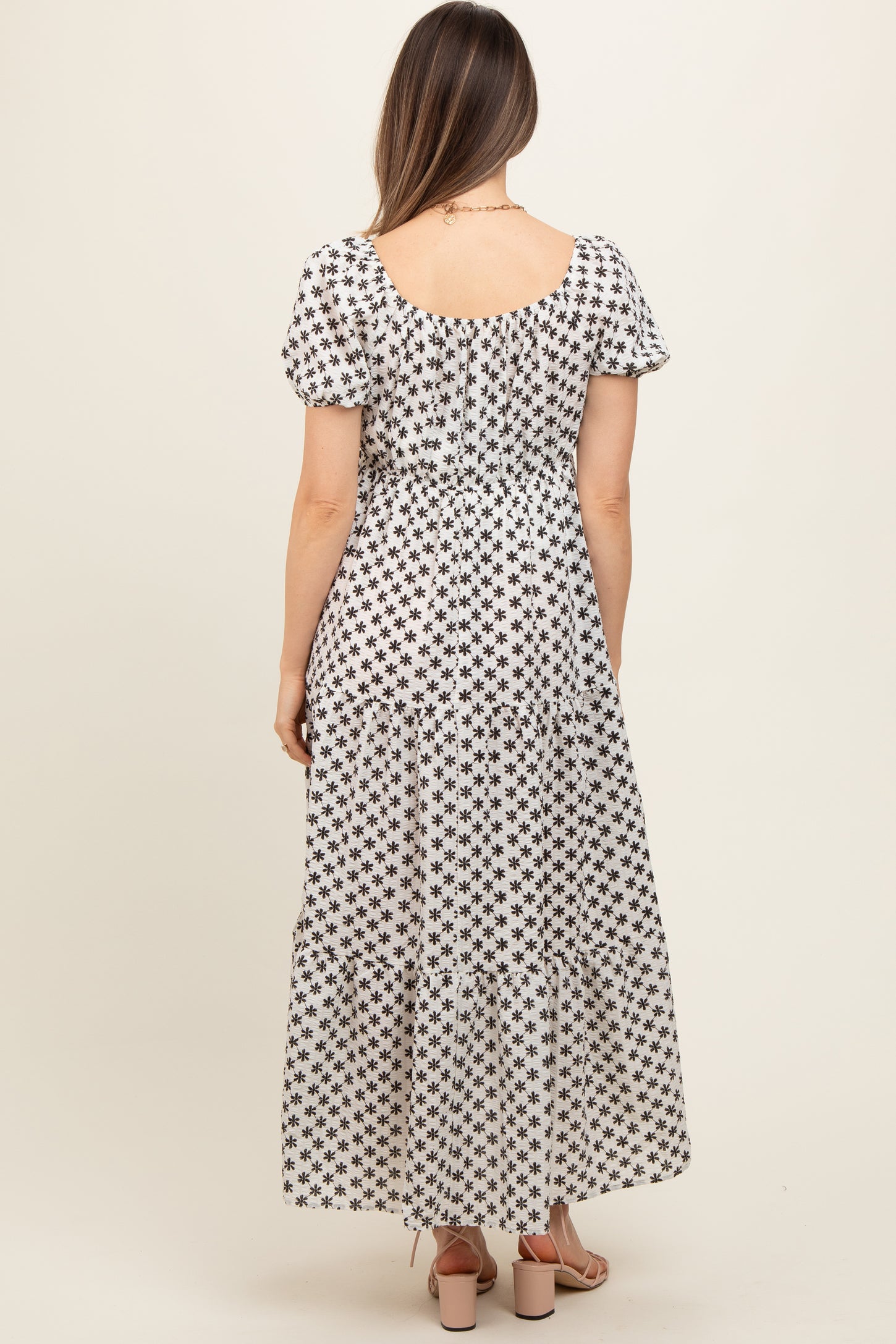 woman wearing a black and white floral print maternity maxi dress with short puff sleeves and tiered hem