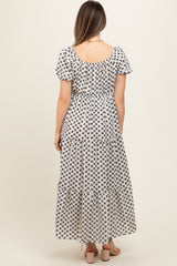 woman wearing a black and white floral print maternity maxi dress with short puff sleeves and tiered hem