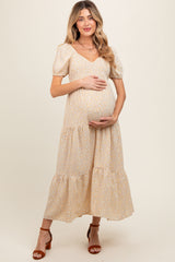 woman wearing a light yellow floral maternity dress with puff sleeves and holding her baby bump