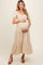 woman wearing a light yellow floral maternity dress with puff sleeves and holding her baby bump