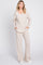 woman wearing a beige ribbed knit loungewear set with a v-neck top and wide-leg pants, posing with hands in pockets