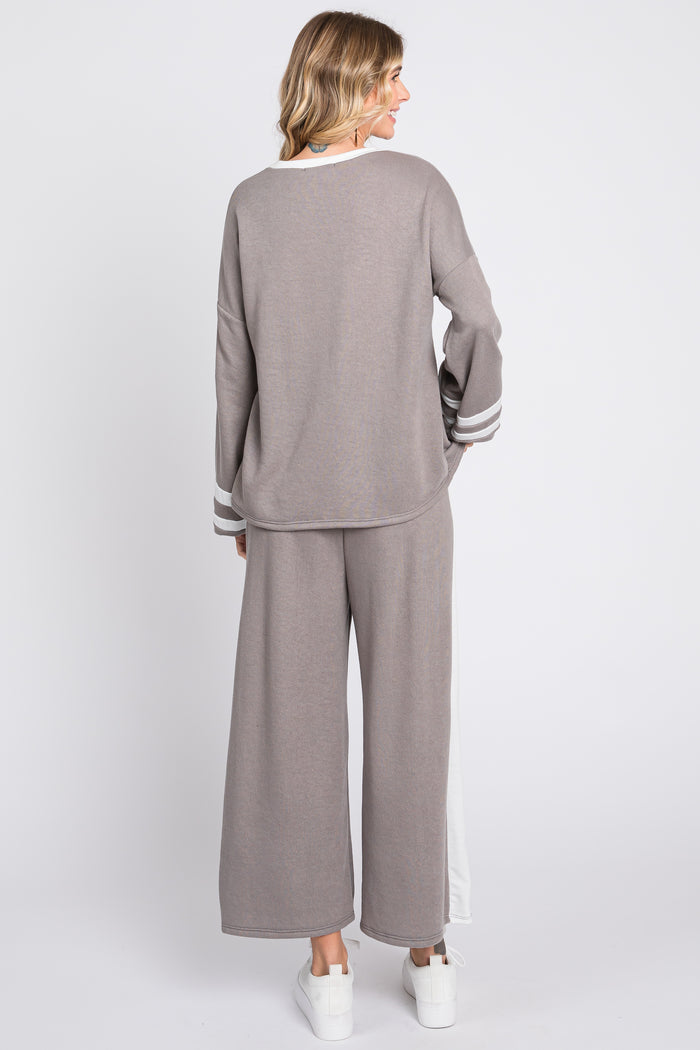 woman wearing a gray long sleeve top with stripes and wide leg pants, viewed from the back