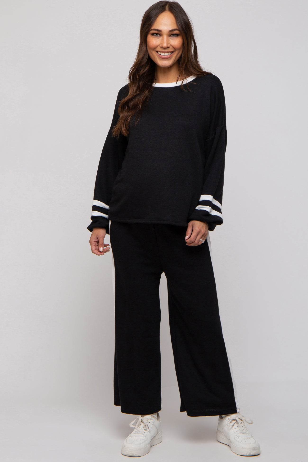 woman wearing a black maternity loungewear set with white striped details and a visible baby bump