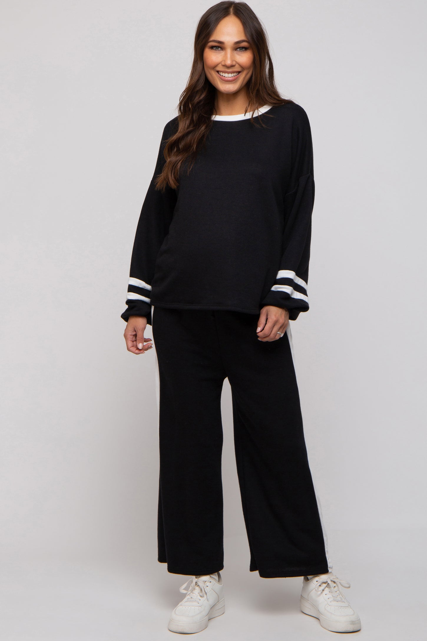 woman wearing a black maternity loungewear set with white striped details and a visible baby bump