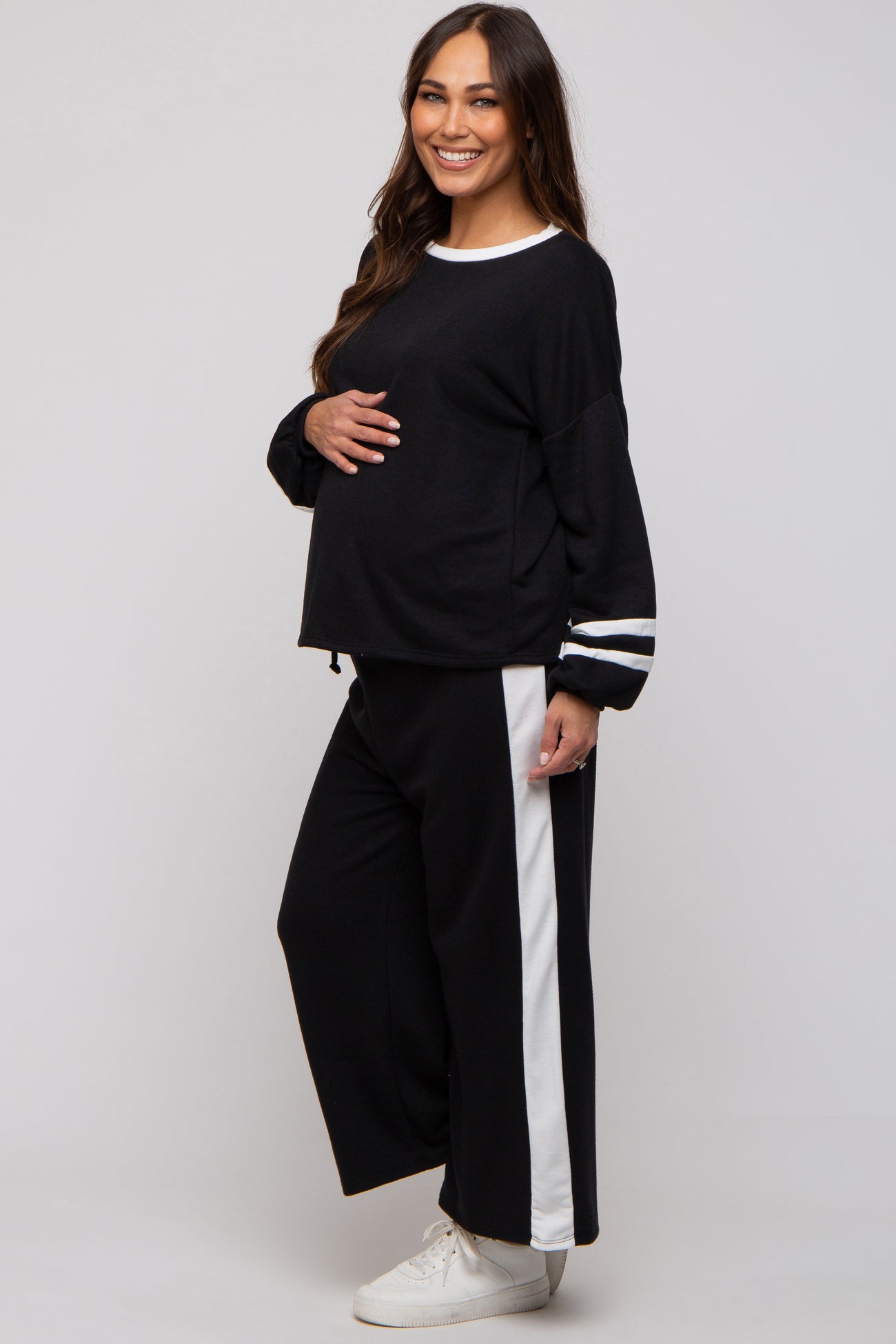 woman wearing a black maternity loungewear set with white stripes, showcasing her baby bump