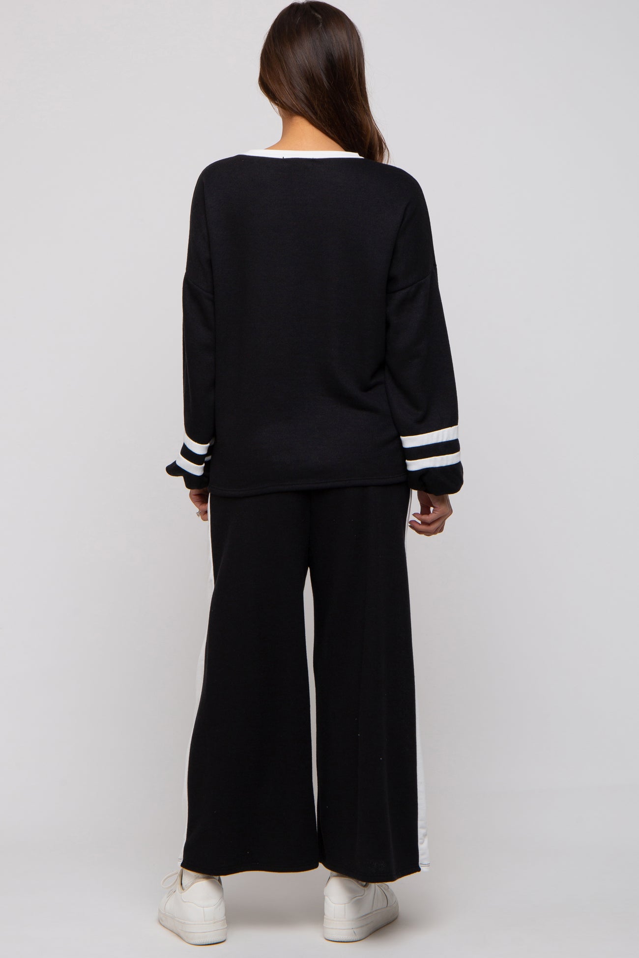 woman wearing a black maternity sweater with white stripes on the sleeves and matching black wide-leg pants