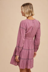 woman wearing a pink long sleeve dress with tiered ruffle hem and lace detailing, shown from the back