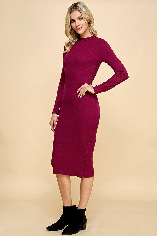woman wearing a burgundy long sleeve fitted ribbed dress with buttons along the hemline and ankle boots