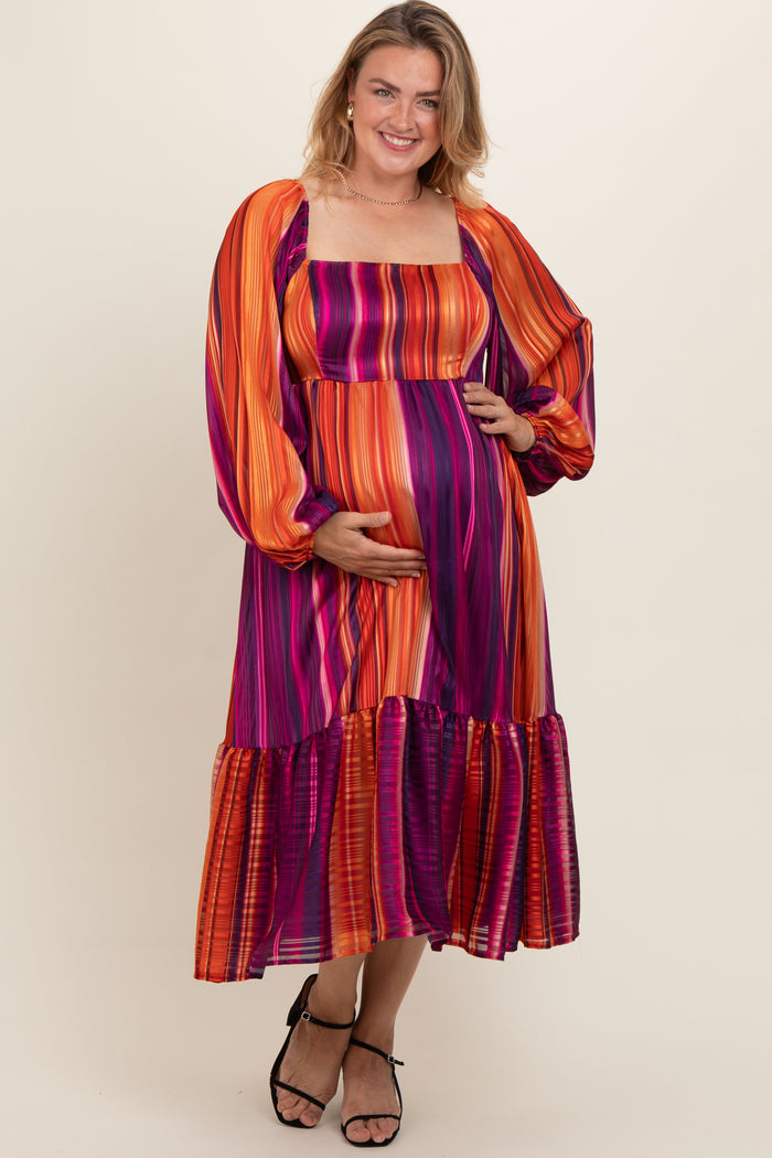 woman wearing a colorful striped maternity dress with long sleeves and a tiered skirt, showing her baby bump
