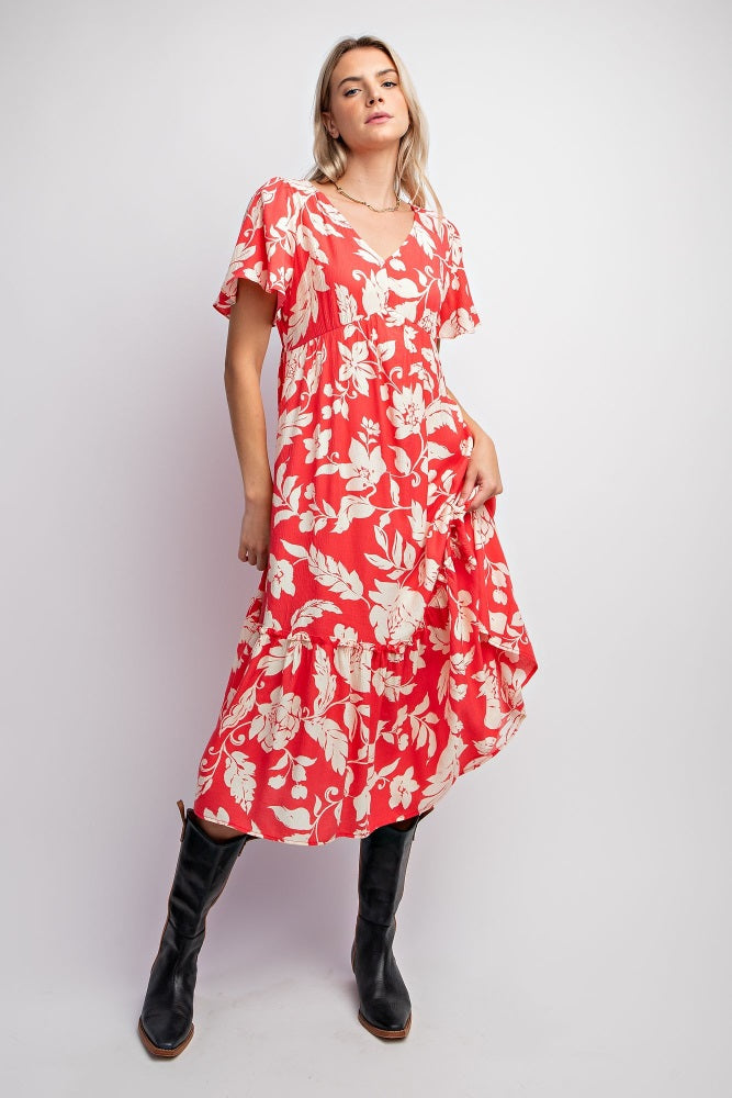 woman wearing a red floral midi dress with short sleeves and a tiered hem, paired with black knee-high boots