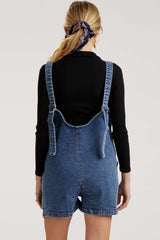 woman wearing a denim maternity overall shorts in a relaxed fit, showing the back view