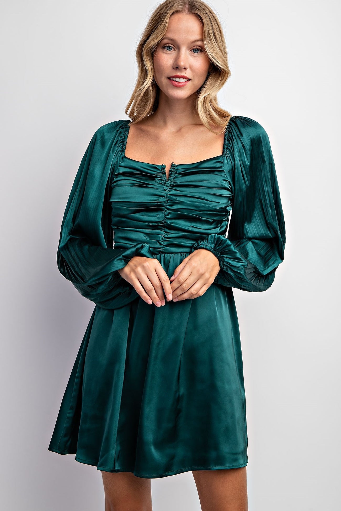 woman wearing a dark green satin mini dress with puff sleeves and a ruched bodice