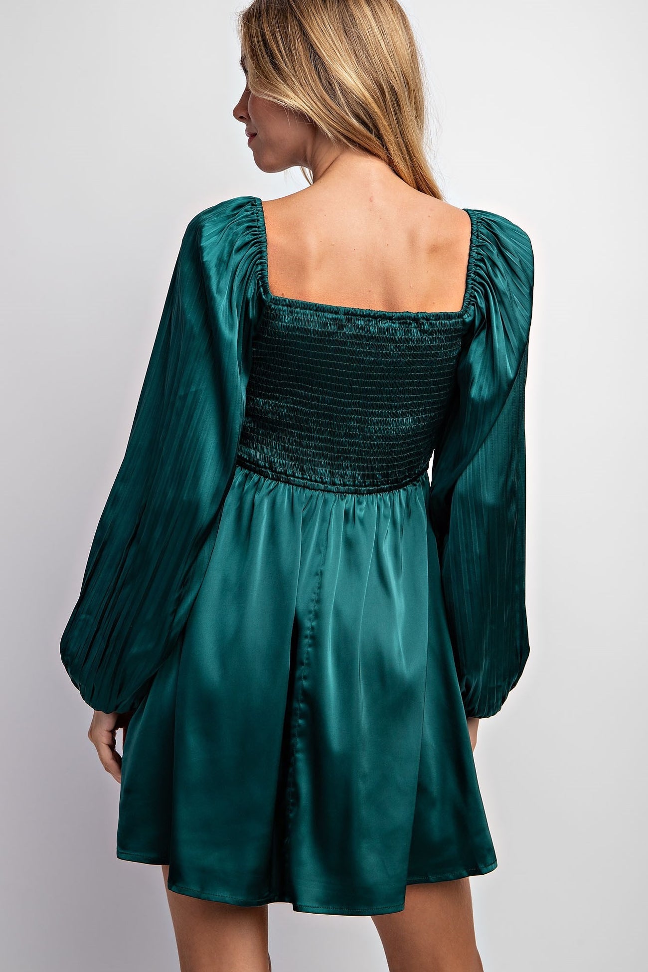 woman wearing a green satin mini dress with puffed sleeves and a smocked bodice, viewed from the back